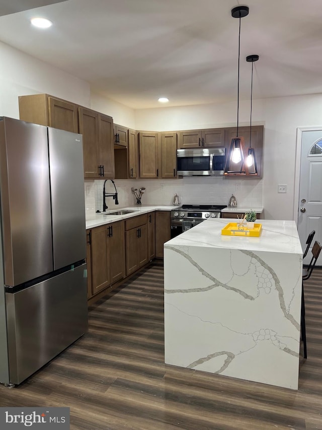 kitchen featuring appliances with stainless steel finishes, sink, backsplash, hanging light fixtures, and dark hardwood / wood-style floors