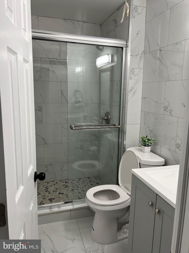 bathroom featuring toilet, vanity, and a shower with door