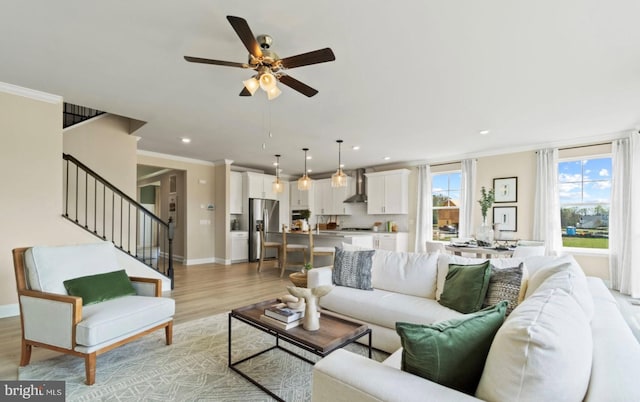 living room with crown molding, light wood-type flooring, and ceiling fan