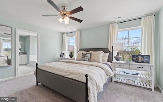 carpeted bedroom with connected bathroom, multiple windows, and ceiling fan