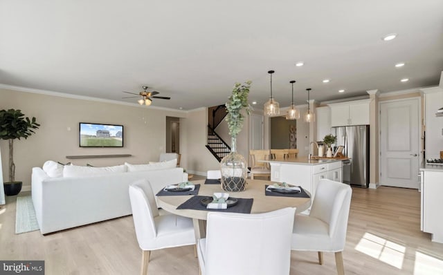 dining space featuring ceiling fan, ornamental molding, and light hardwood / wood-style flooring