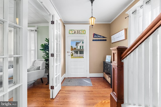 entryway with light hardwood / wood-style flooring and crown molding