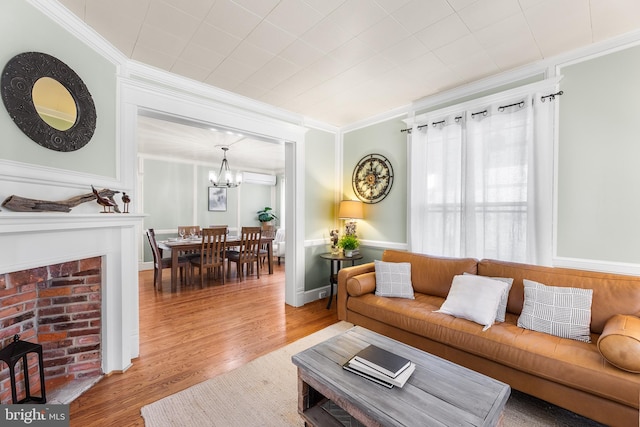 living room with crown molding, hardwood / wood-style flooring, a chandelier, and a wall mounted air conditioner