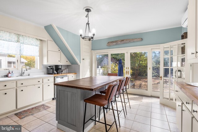 kitchen featuring ornamental molding, white cabinetry, decorative light fixtures, and butcher block counters