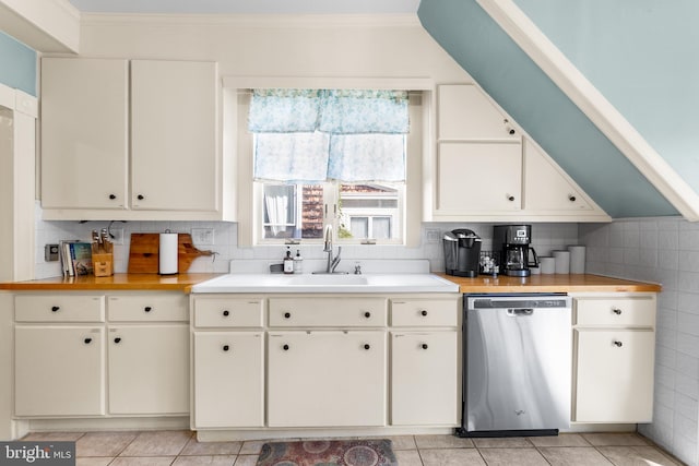 kitchen featuring dishwasher, decorative backsplash, sink, light tile patterned flooring, and white cabinetry