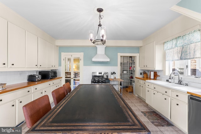 kitchen featuring decorative backsplash, hanging light fixtures, white cabinets, premium range hood, and appliances with stainless steel finishes