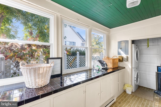 interior space with stacked washer and dryer, wood ceiling, and white cabinets