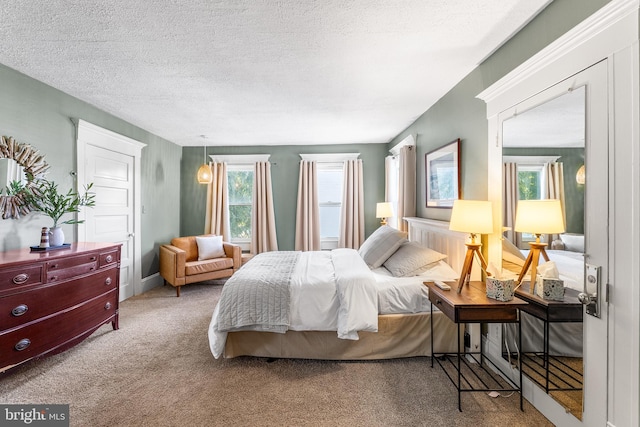 bedroom featuring a textured ceiling, multiple windows, and carpet flooring