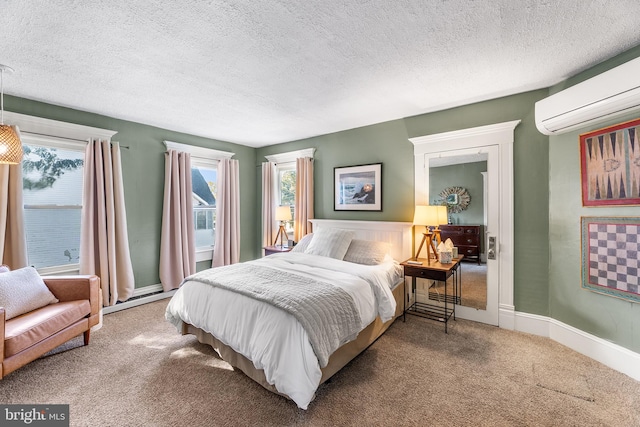 bedroom with a wall mounted air conditioner, carpet floors, and a textured ceiling