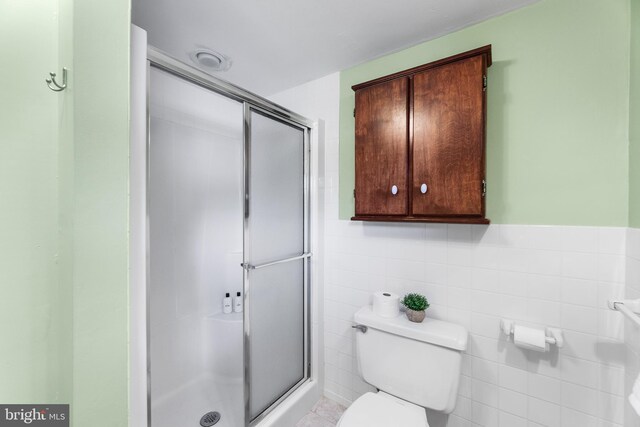 bathroom featuring toilet, tile walls, and an enclosed shower