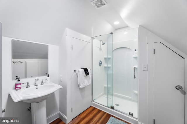 bathroom with lofted ceiling, a shower with shower door, and wood-type flooring