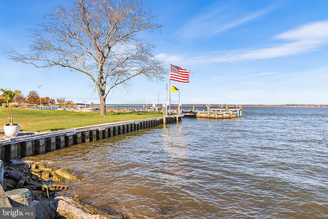 view of dock with a lawn and a water view