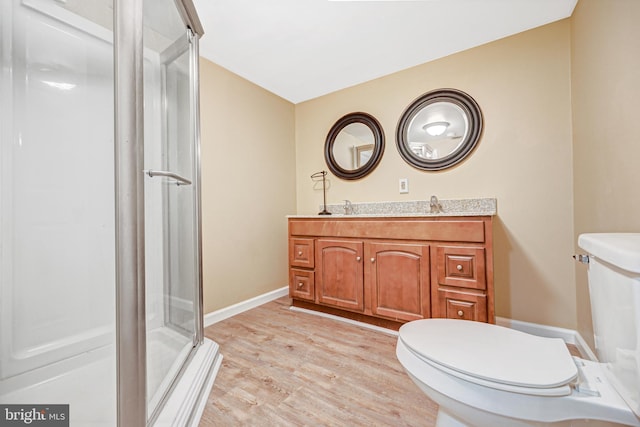 bathroom featuring vanity, wood-type flooring, a shower with shower door, and toilet