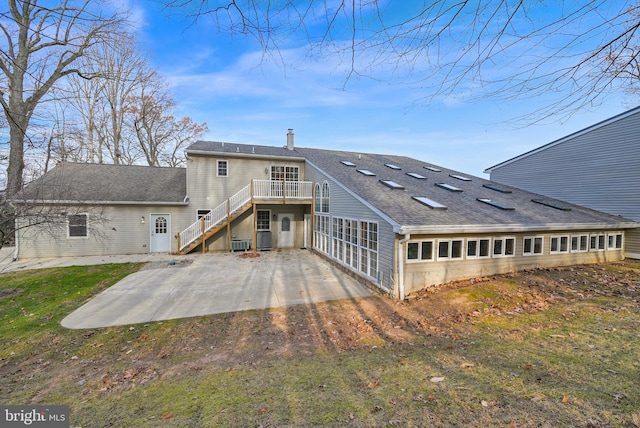 rear view of property with cooling unit, a patio area, and a lawn