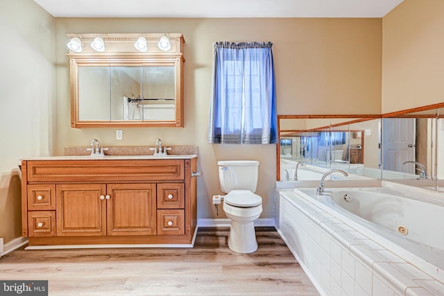 bathroom featuring hardwood / wood-style floors, vanity, a relaxing tiled tub, and toilet