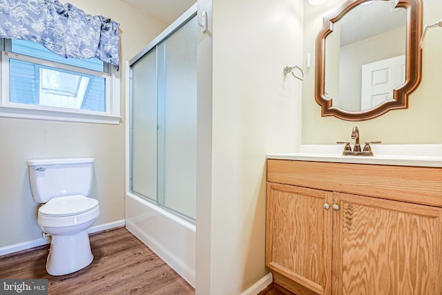 full bathroom featuring combined bath / shower with glass door, vanity, hardwood / wood-style flooring, and toilet