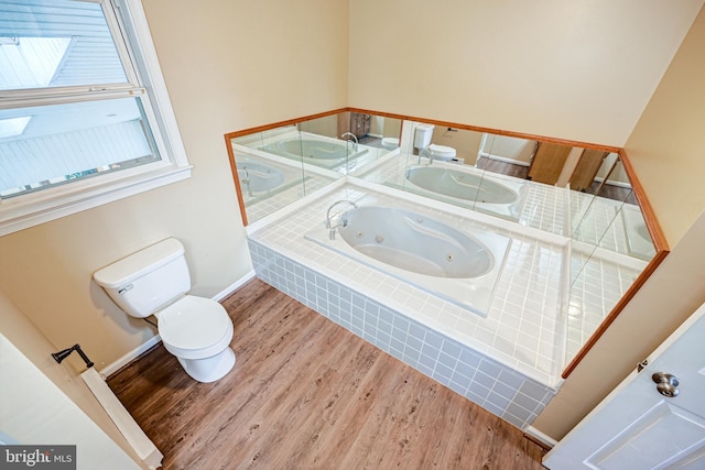 bathroom featuring hardwood / wood-style floors, tiled bath, toilet, and sink