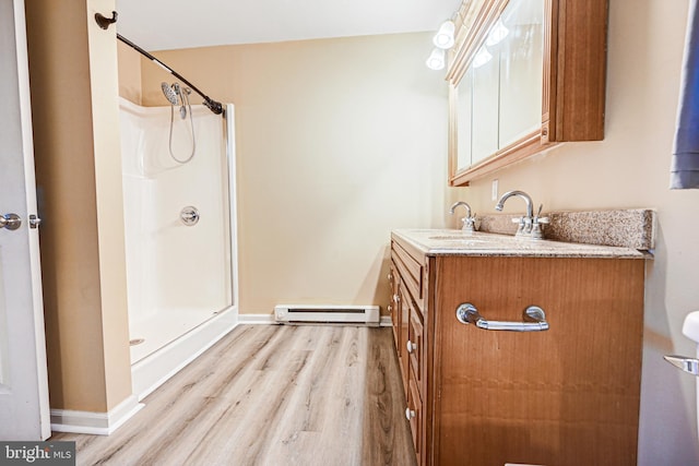 bathroom featuring hardwood / wood-style flooring, vanity, walk in shower, and a baseboard heating unit