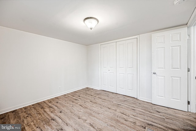 unfurnished bedroom with light wood-type flooring and a closet