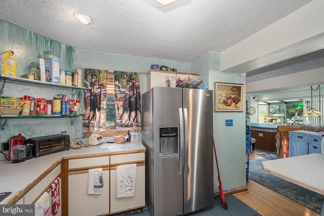 kitchen featuring a textured ceiling, light hardwood / wood-style flooring, and stainless steel refrigerator with ice dispenser