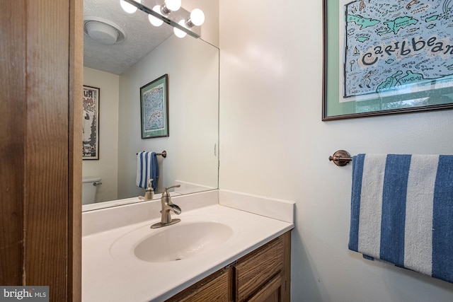 bathroom with vanity, toilet, and a textured ceiling