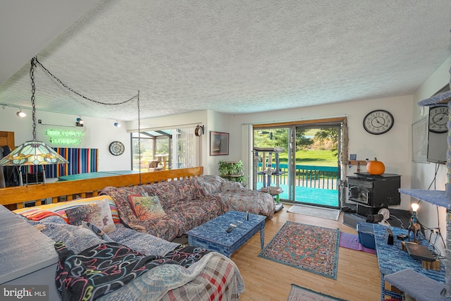 living room featuring light hardwood / wood-style flooring, a textured ceiling, and a wood stove