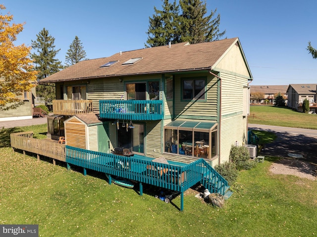 rear view of house with a deck, a lawn, and a balcony