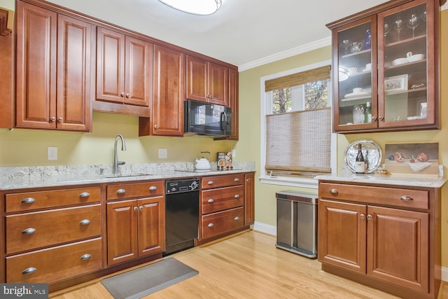 kitchen featuring sink, black appliances, light stone countertops, crown molding, and light wood-type flooring