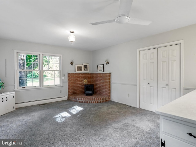 unfurnished living room featuring light carpet, a baseboard heating unit, a brick fireplace, and ceiling fan