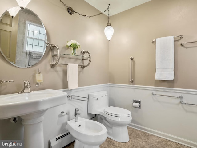 bathroom with toilet, a baseboard radiator, and a bidet