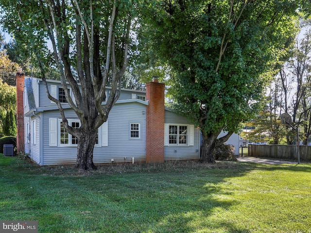 back of house featuring central air condition unit and a lawn