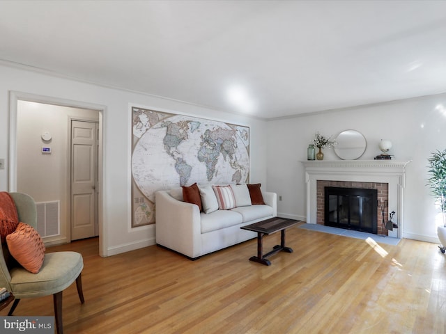 living room featuring light hardwood / wood-style flooring and a brick fireplace