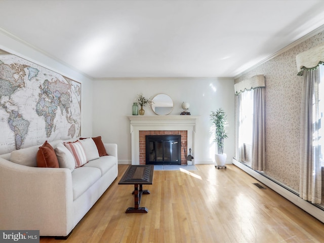 living room featuring light hardwood / wood-style floors, crown molding, baseboard heating, and a fireplace