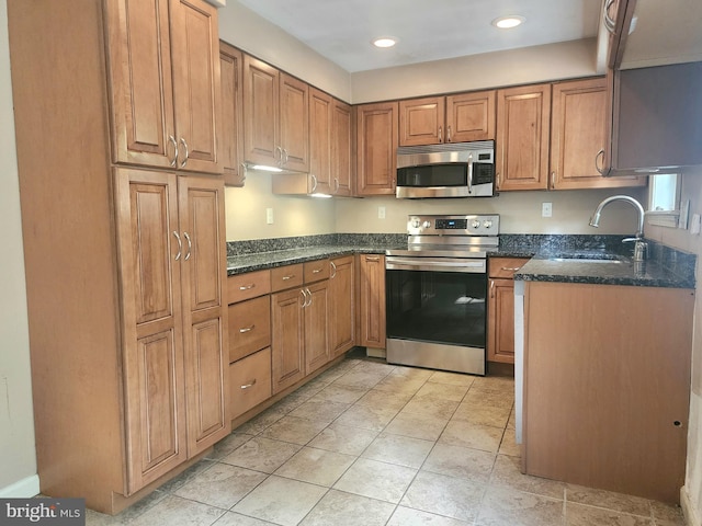 kitchen with appliances with stainless steel finishes, sink, and dark stone counters