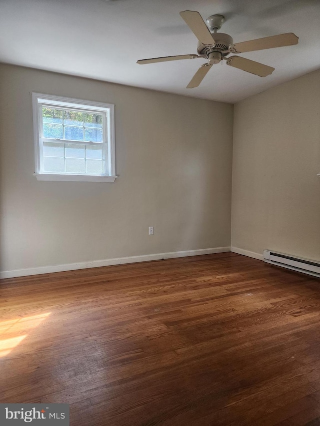 unfurnished room featuring ceiling fan, dark hardwood / wood-style flooring, and a baseboard heating unit