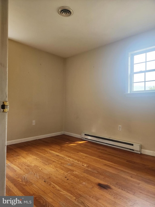 empty room featuring baseboard heating and light wood-type flooring