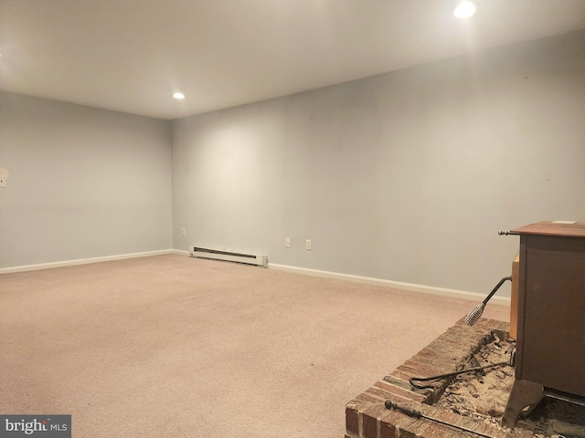 carpeted empty room featuring a baseboard heating unit