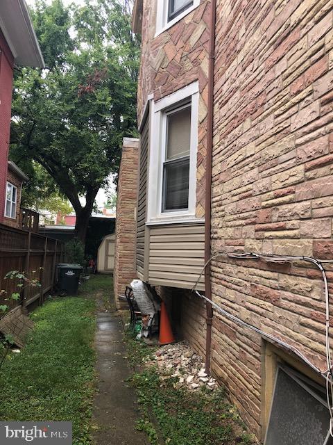 view of home's exterior with a storage unit, an outbuilding, stone siding, and fence