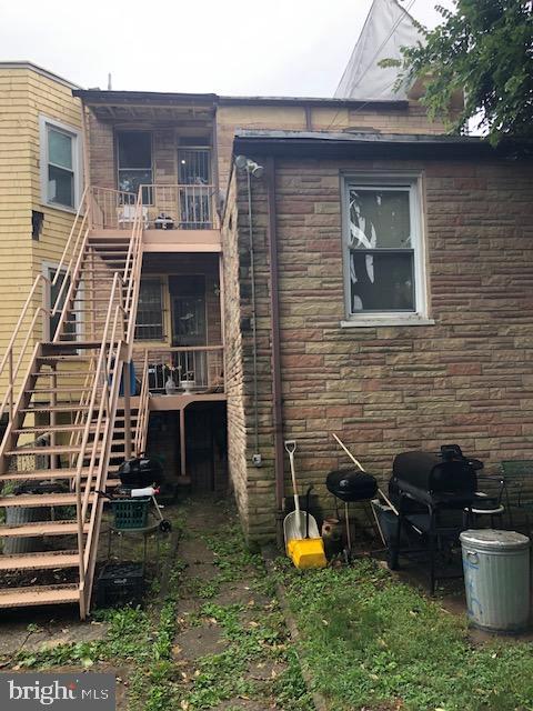 back of property with a balcony, stone siding, and stairway