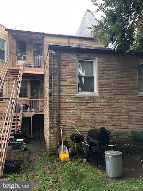 exterior space with a balcony, stone siding, and stairs