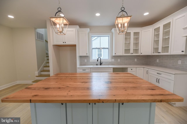 kitchen with sink, a center island, white cabinetry, and light wood-type flooring