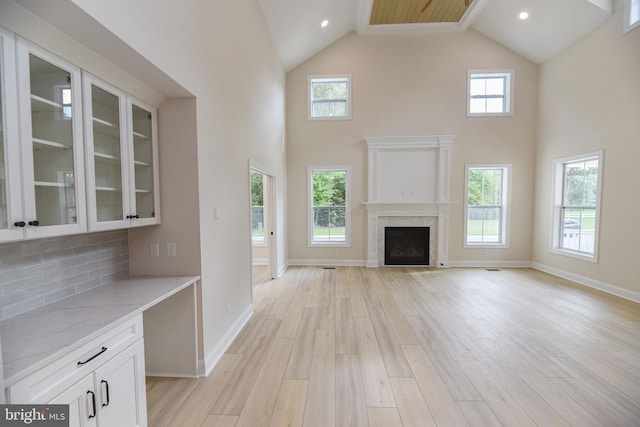 unfurnished living room featuring light hardwood / wood-style flooring, high vaulted ceiling, and plenty of natural light