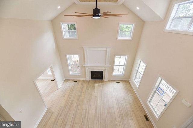 unfurnished living room featuring light hardwood / wood-style floors, a healthy amount of sunlight, high vaulted ceiling, and beamed ceiling