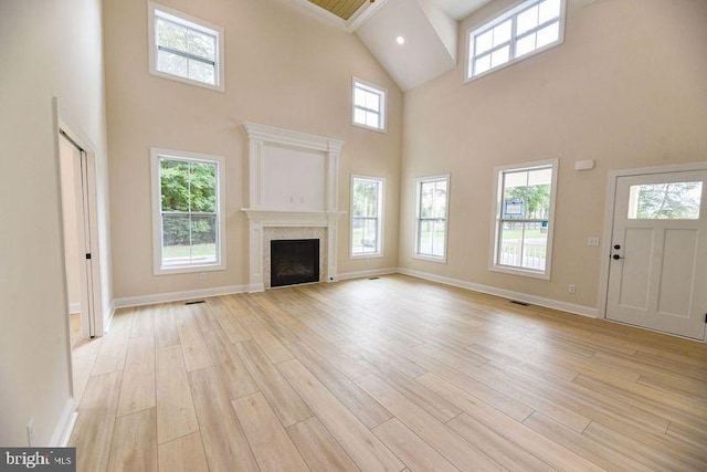 unfurnished living room featuring a high ceiling and light hardwood / wood-style floors