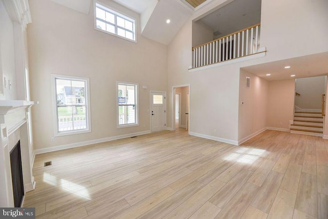 unfurnished living room with a towering ceiling and light hardwood / wood-style floors