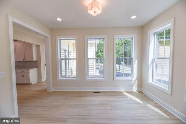 unfurnished dining area featuring light wood-type flooring and a wealth of natural light