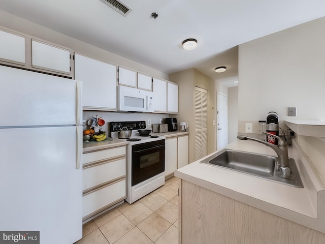 kitchen with white appliances, light tile patterned floors, sink, and white cabinets