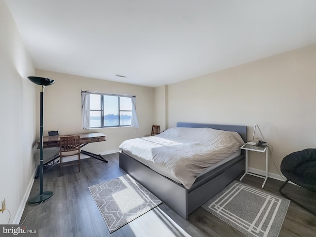 bedroom featuring baseboards, wood finished floors, and visible vents
