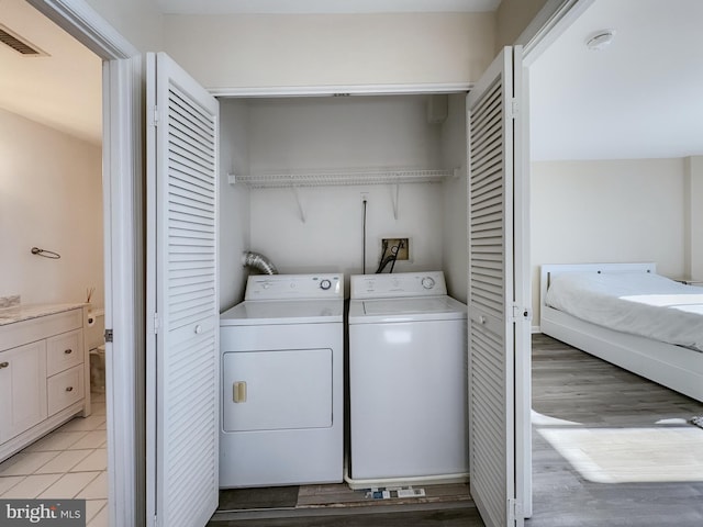 laundry area with washer and clothes dryer, light wood-style floors, visible vents, and laundry area