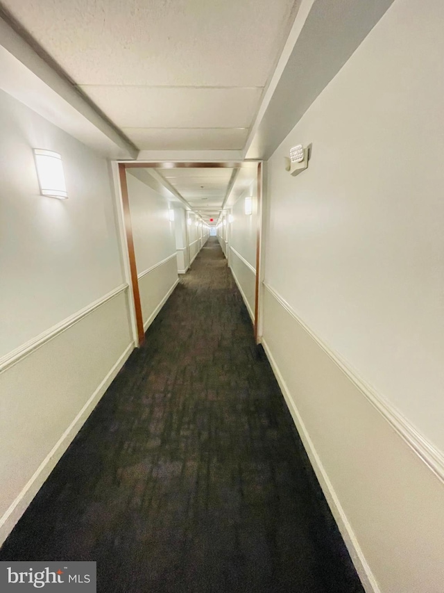 corridor featuring baseboards and carpet flooring